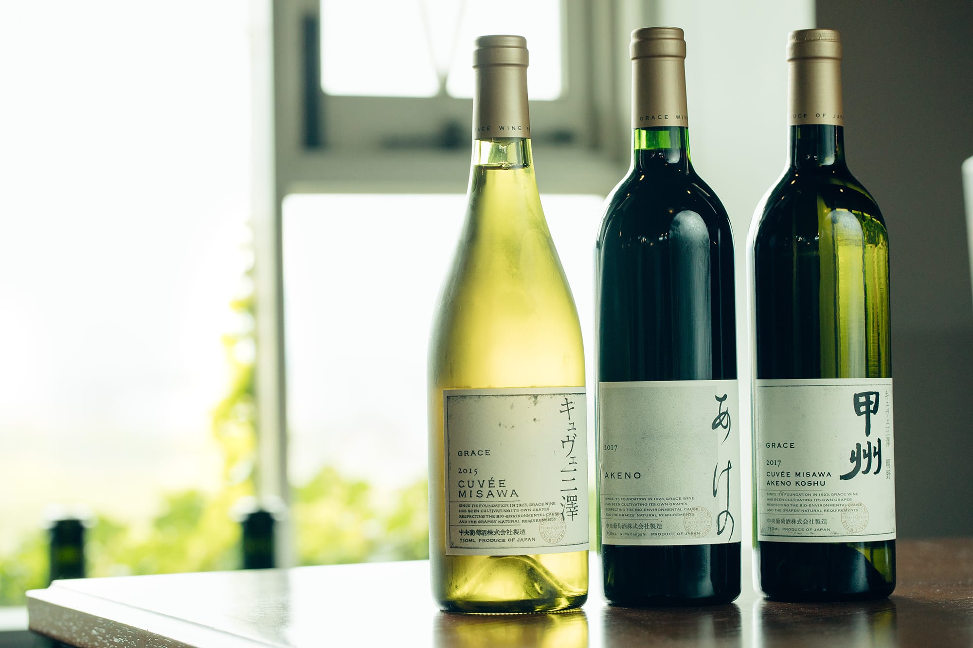 （右）2014年のDWWAで金賞を受賞したものと同じ「キュヴェ三澤 明野甲州」。（中央）新登場の「あけの」。現在、赤ワインは品種よりも産地の個性を表現する方向で、三澤農場の最高峰「キュヴェ三澤」のセカンドラベルの役割を果たす。メルロー、カベルネ・ソーヴィニヨン、カベルネ・フラン、プティ・ヴェルドをブレンドした、ボルドースタイルの赤。（左）90年代から高い評価を得る「キュヴェ三澤」の白。シャルドネ100パーセント。全てラベルデザインはグラフィックデザイナーの原研哉によるもの。